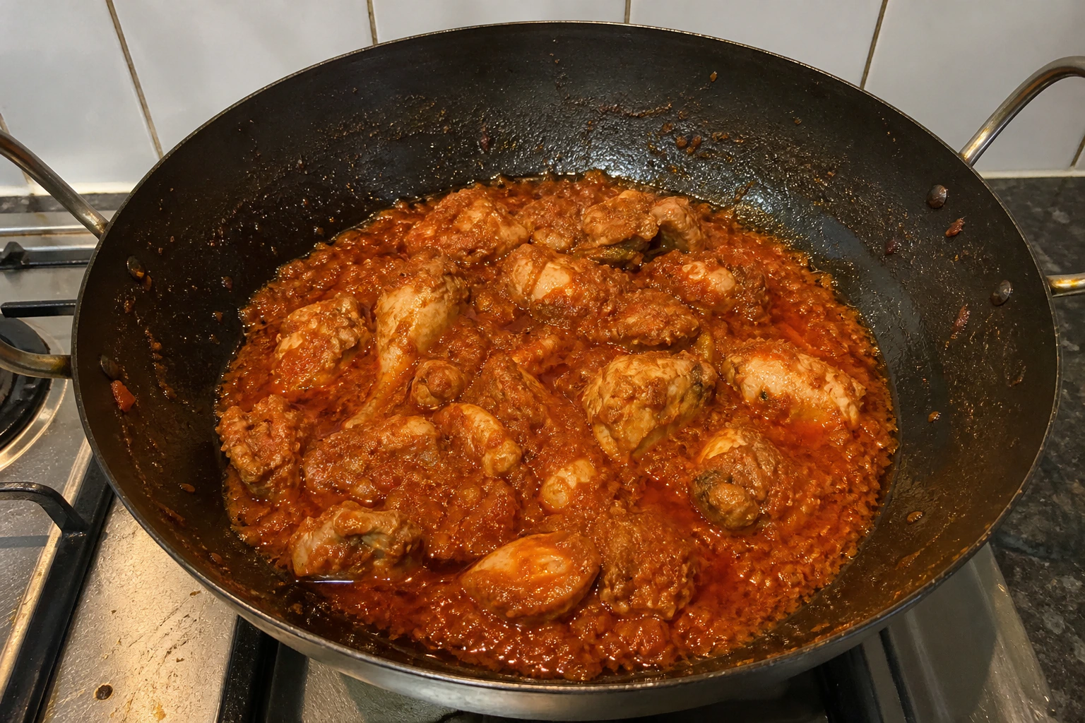 Thick chicken karahi masala with small beads of oil visibly separating around the edge of the pan