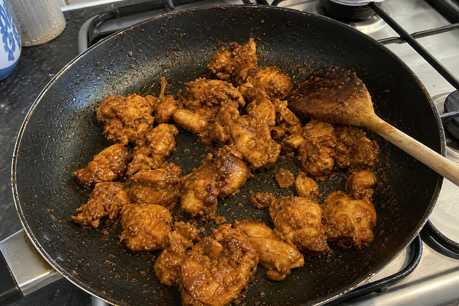 Irregular chicken pieces alone in a frying pan with reduced Lahori masala clinging and no loose liquid