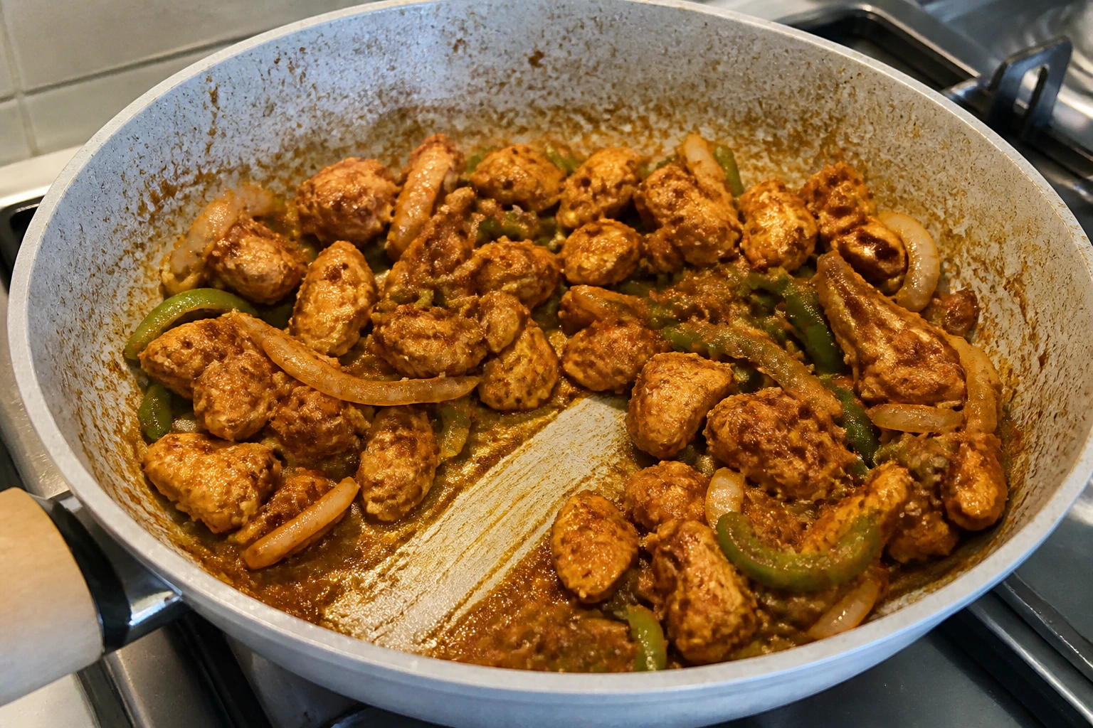 Browned chicken pieces coated in a thick reduced masala with no watery liquid in the frying pan