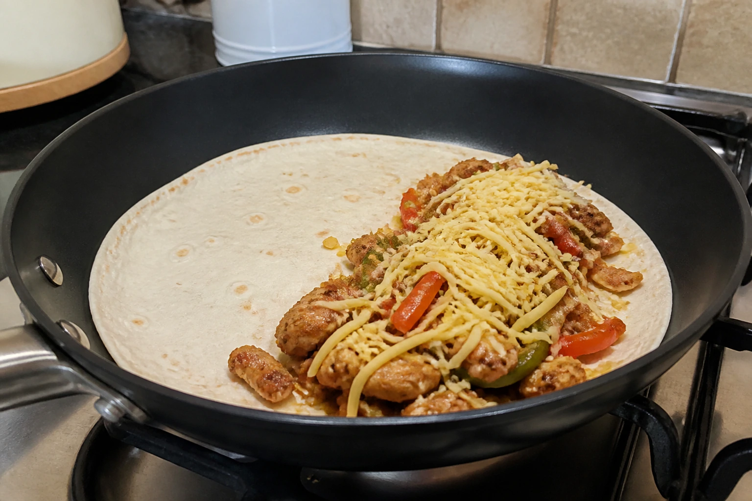 A tortilla in a frying pan with a thin even layer of chicken filling and cheese leaving a clear border