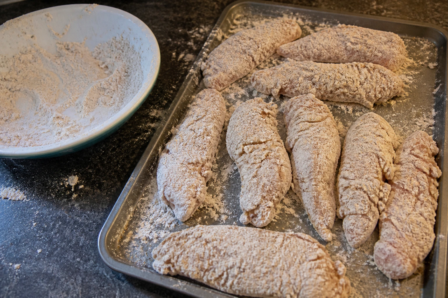 Seasoned flour with small yoghurt marinade clumps forming a craggy coating for chicken tenders