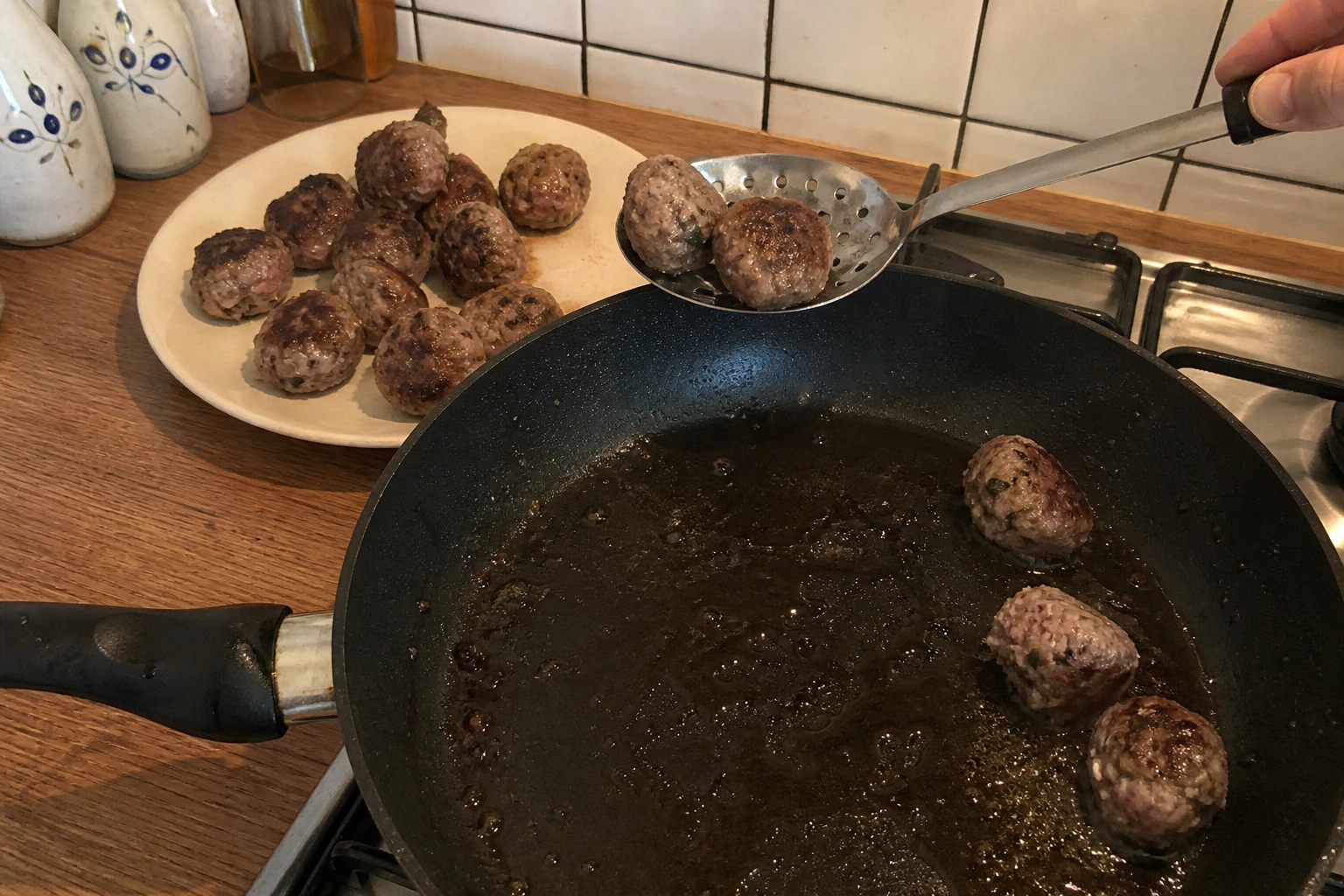 Irregular hand-rolled lamb meatballs being removed in batches after uneven pan browning