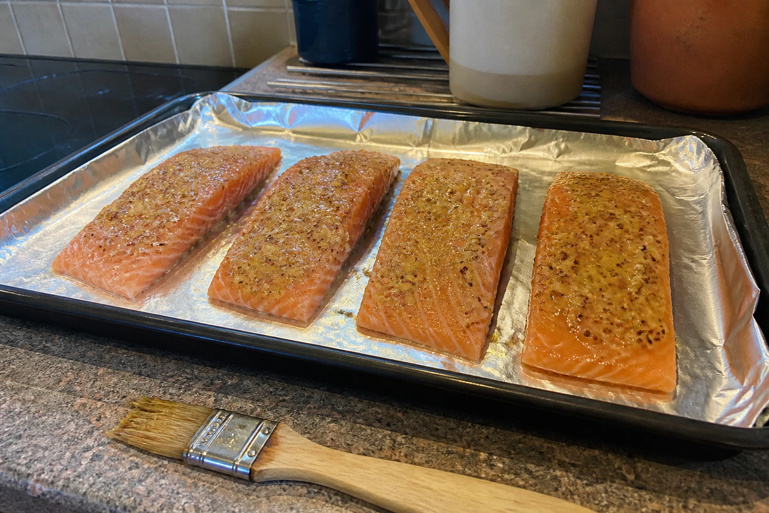 Salmon fillets evenly coated with a thick mustard yoghurt marinade on a lined kitchen tray