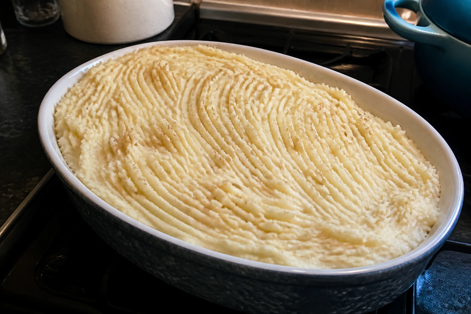 Shepherd's pie before baking with mash spread to the edges and rough fork ridges across the top