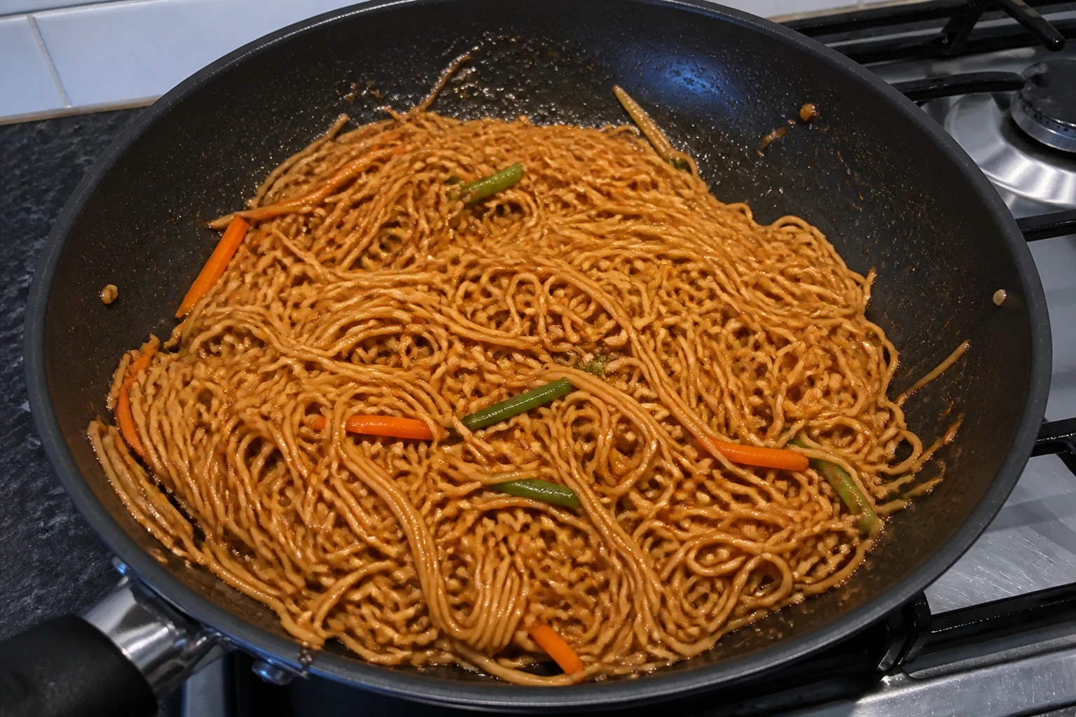 Soy sesame noodles evenly coated in a glossy clinging sauce with no puddle in the wok