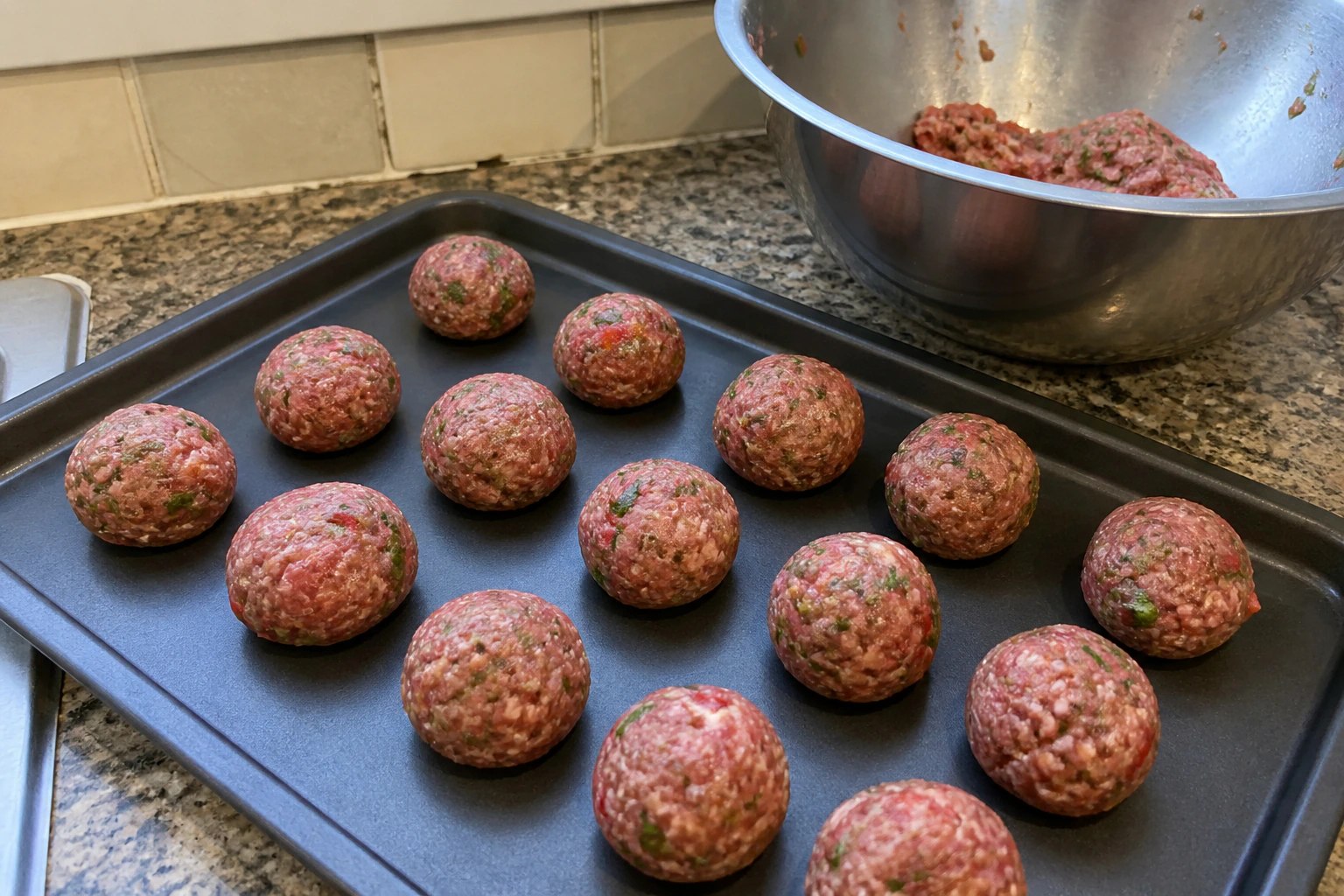 Sixteen evenly shaped lightly packed meatballs arranged on a plate before browning