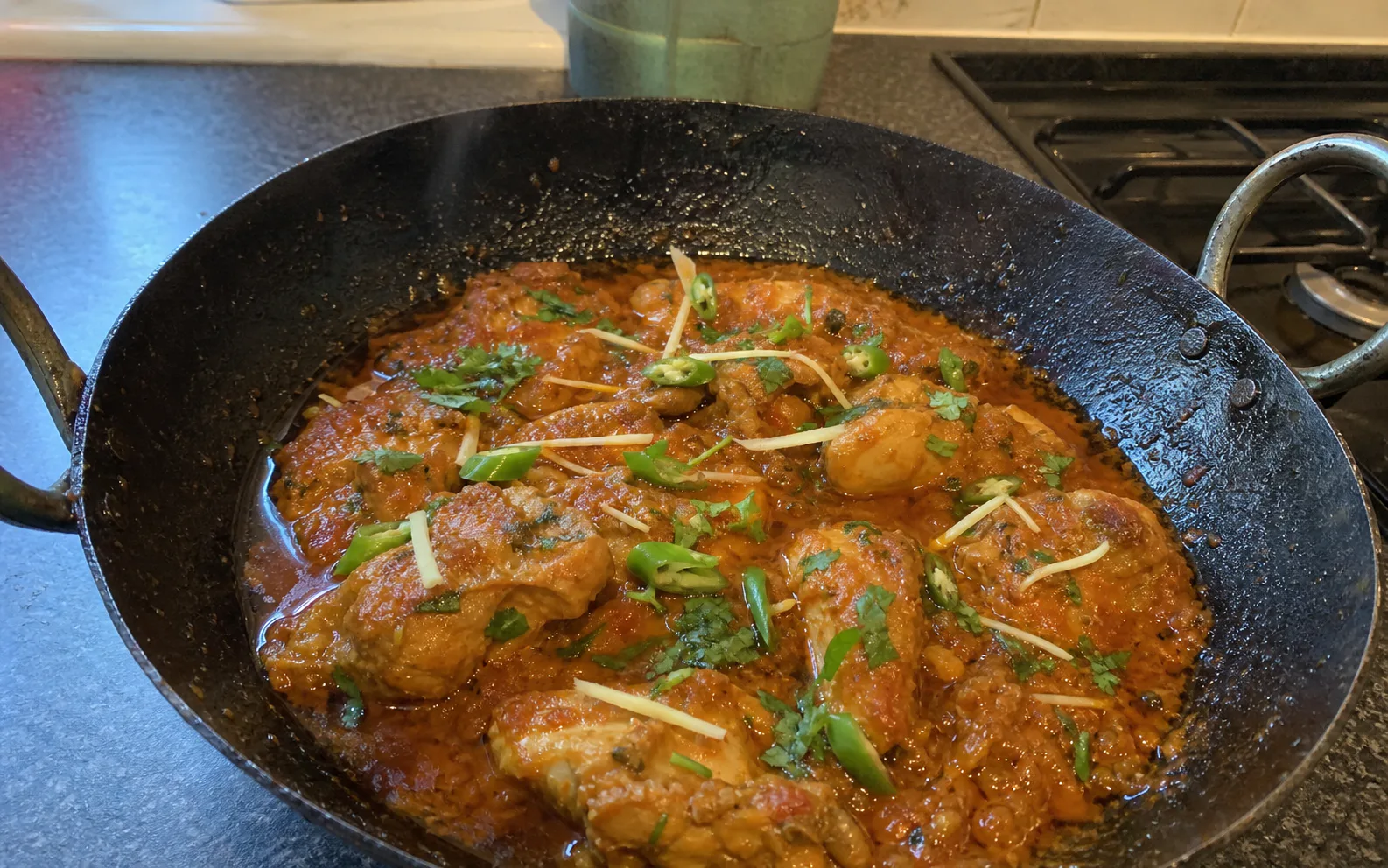 Classic chicken karahi in a black karahi, finished with ginger, green chilli and coriander in a home kitchen