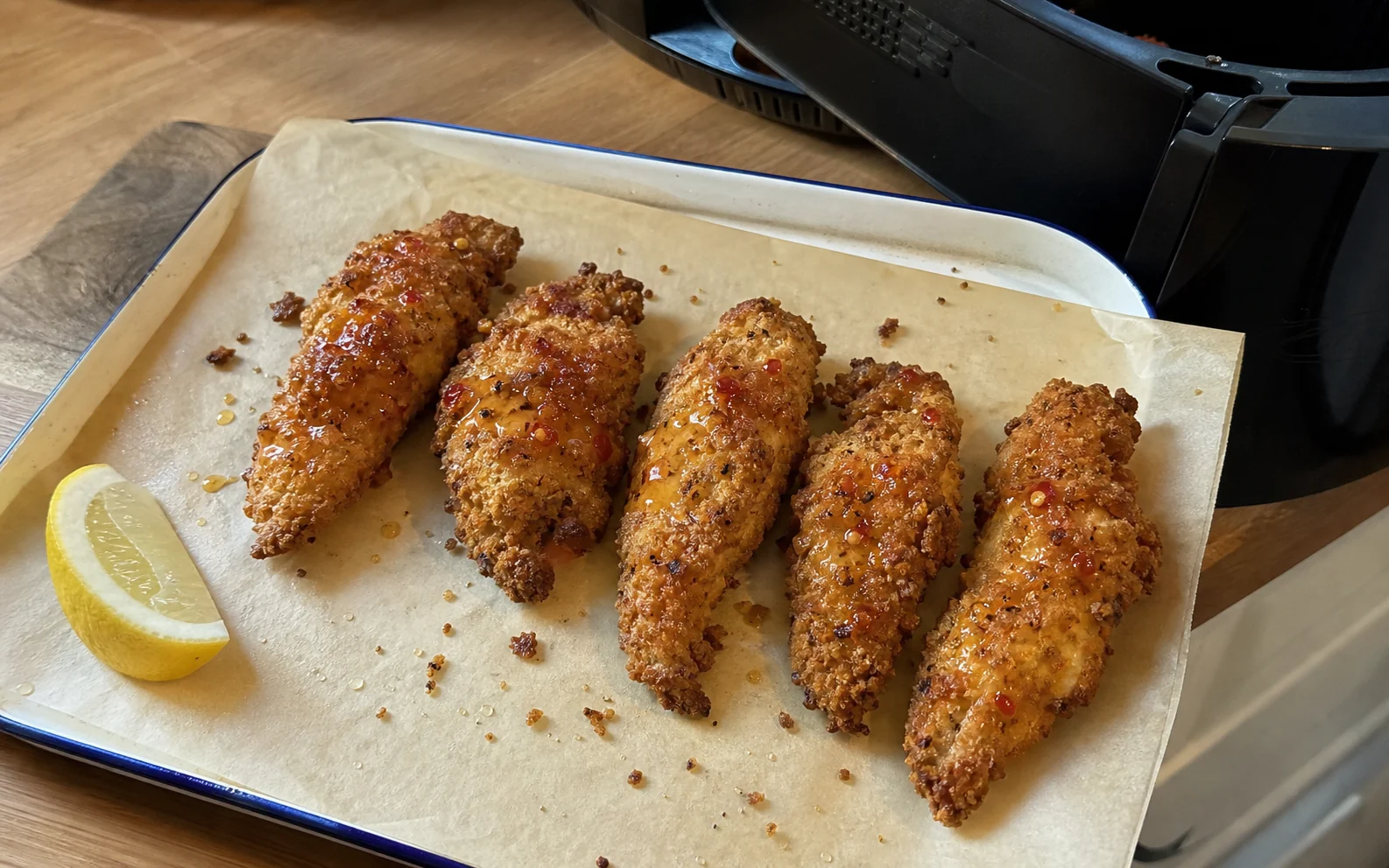 Air-fried crispy chicken tenders with a light hot honey drizzle beside the air fryer