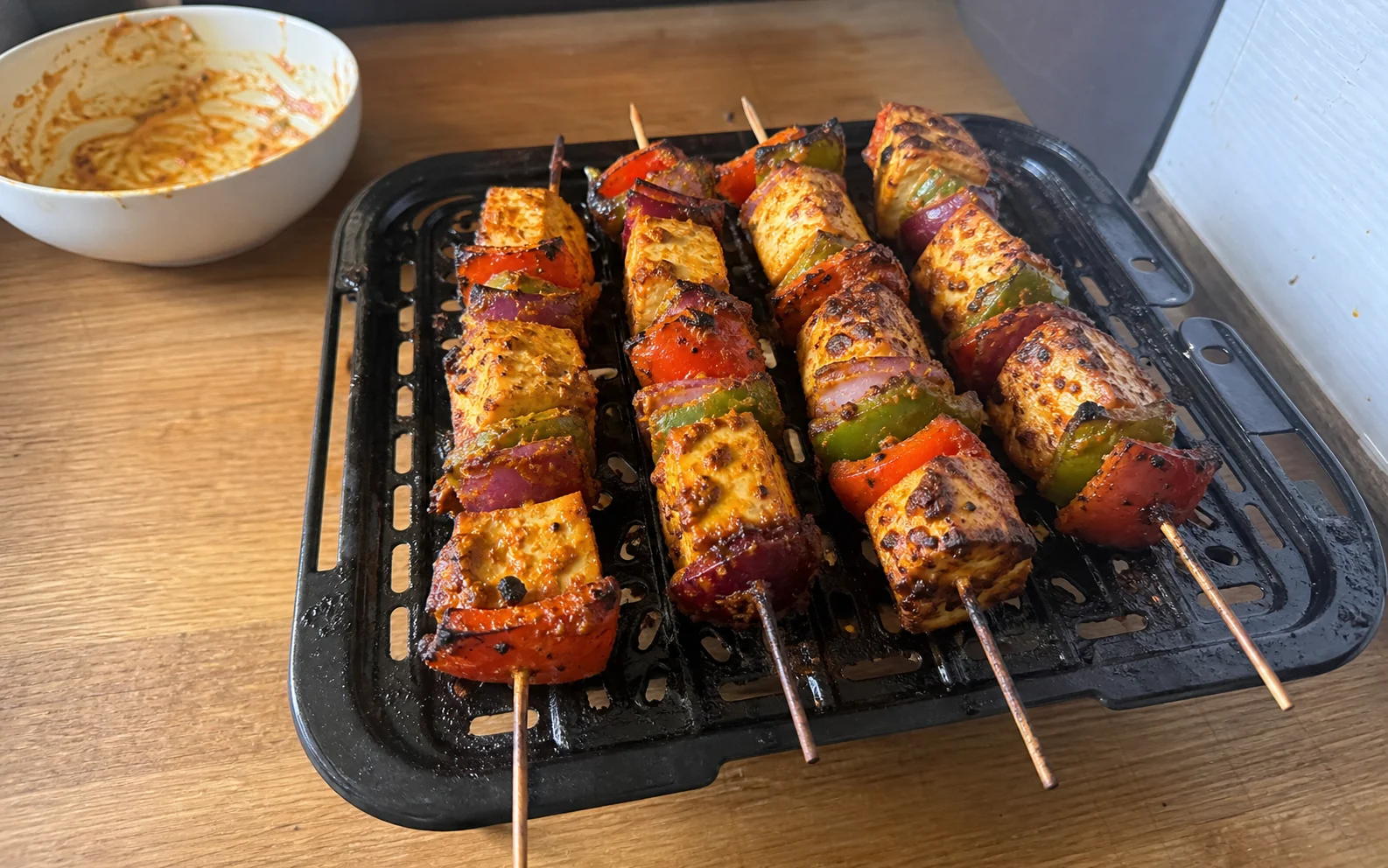 Charred paneer, pepper and red onion skewers on an air-fryer rack