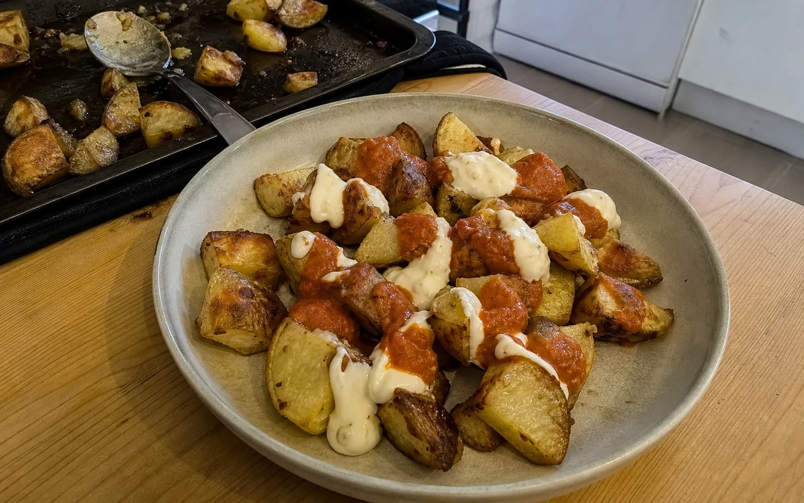 Roasted patatas bravas with modest tomato sauce and aioli beside the used roasting tray