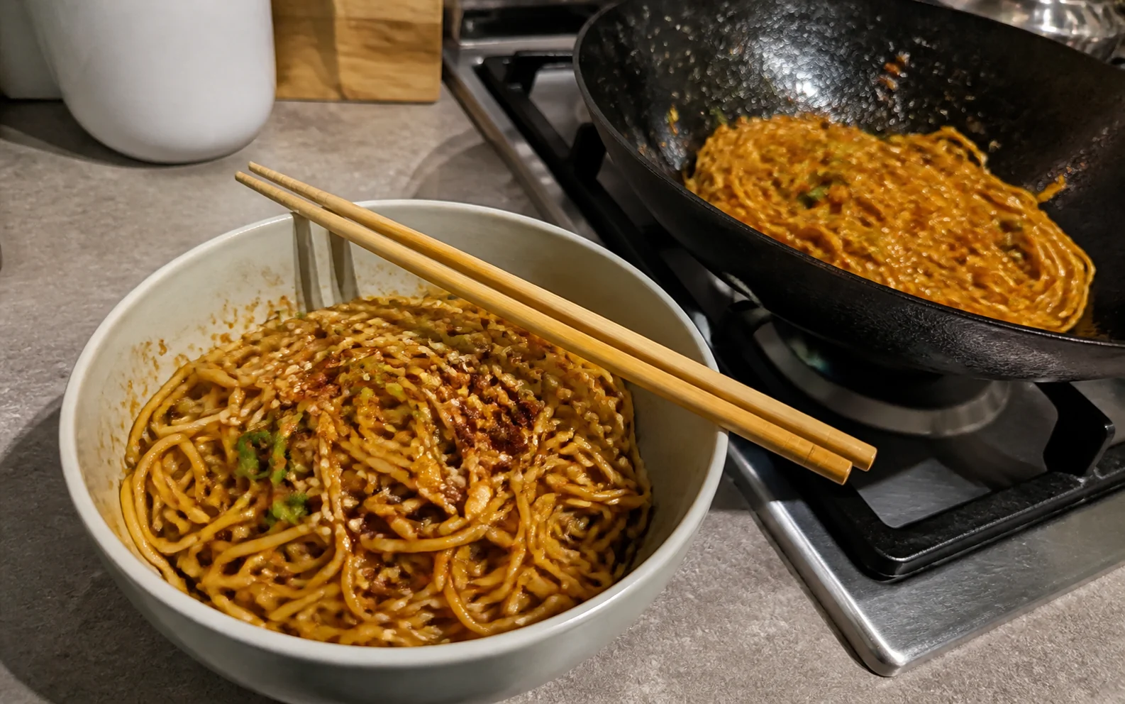 Soy and sesame garlic noodles with spring onion and chilli crisp beside the wok