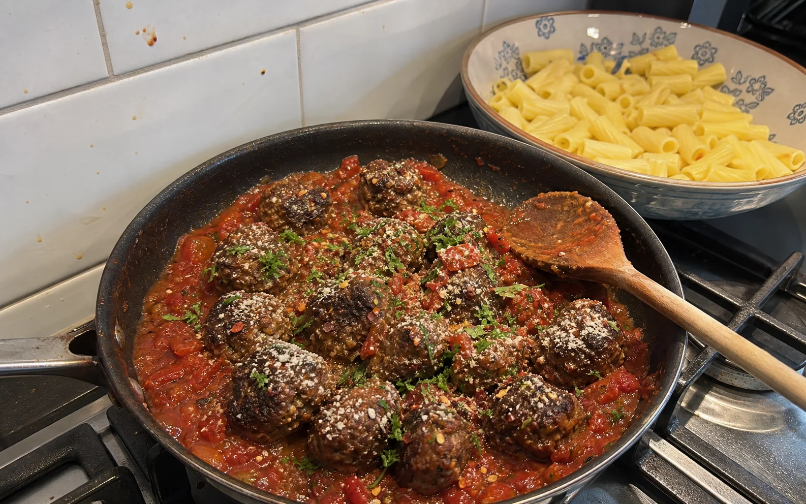 Spicy tomato meatballs with parsley and vegetarian hard cheese cooking on the hob