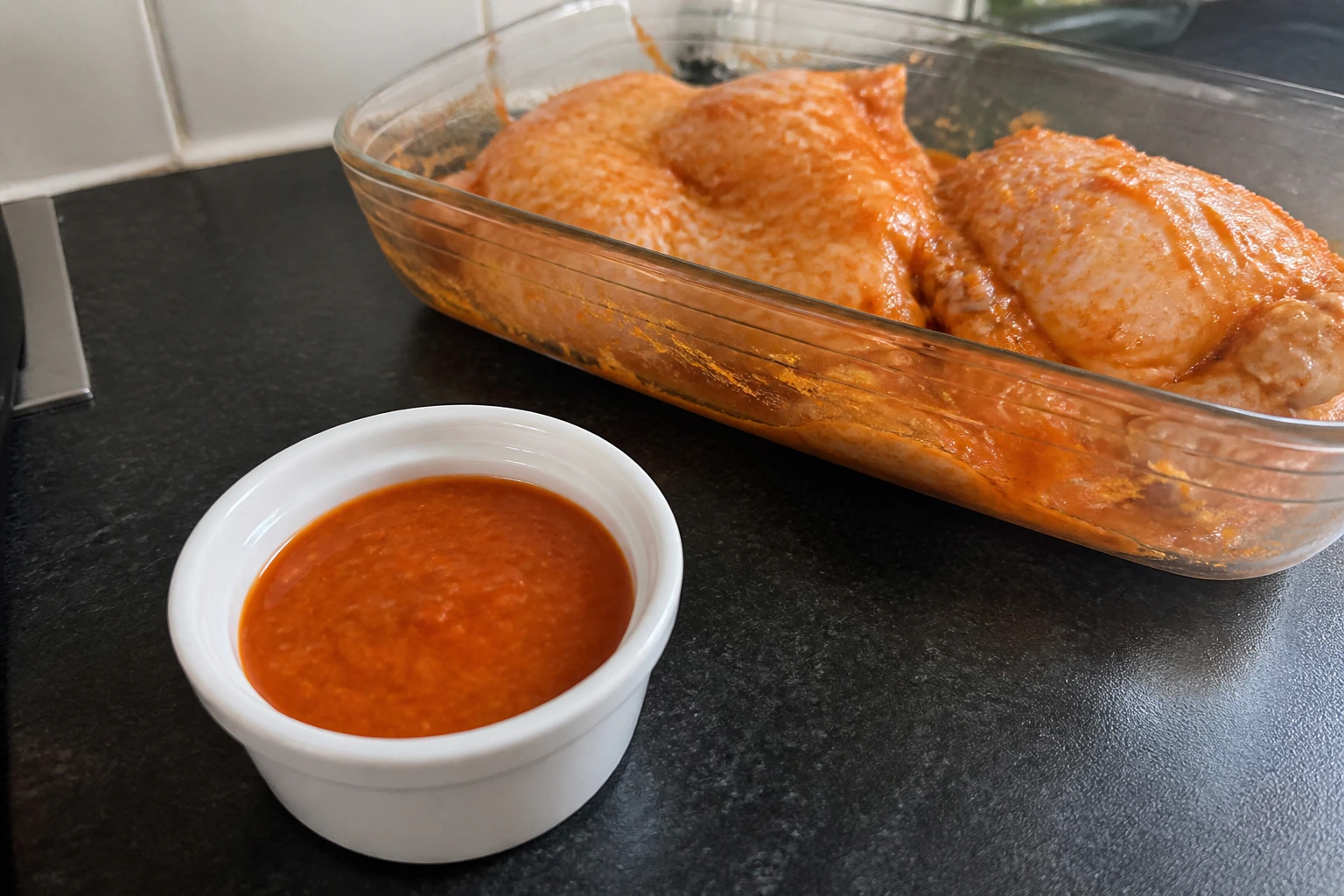 Fresh peri-peri sauce divided into two clearly separate bowls before one portion touches raw chicken