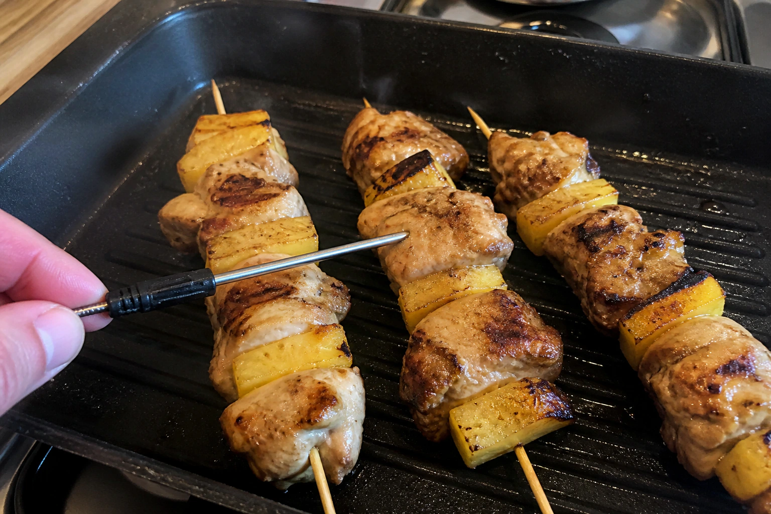 Homemade chicken and pineapple skewers with the centre chicken piece checked by a probe