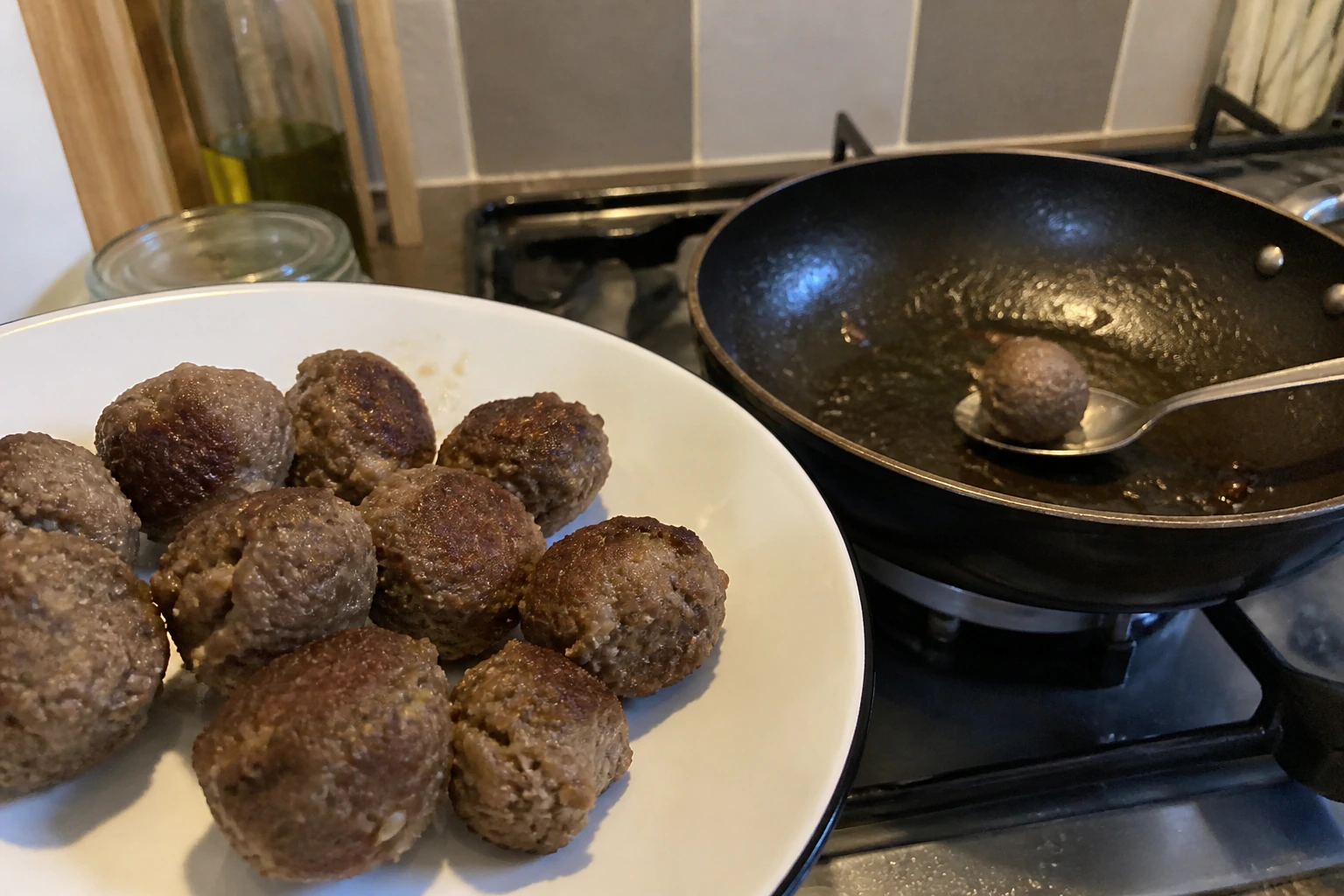 Irregular hand-rolled meatballs removed after varied surface browning before the tomato sauce
